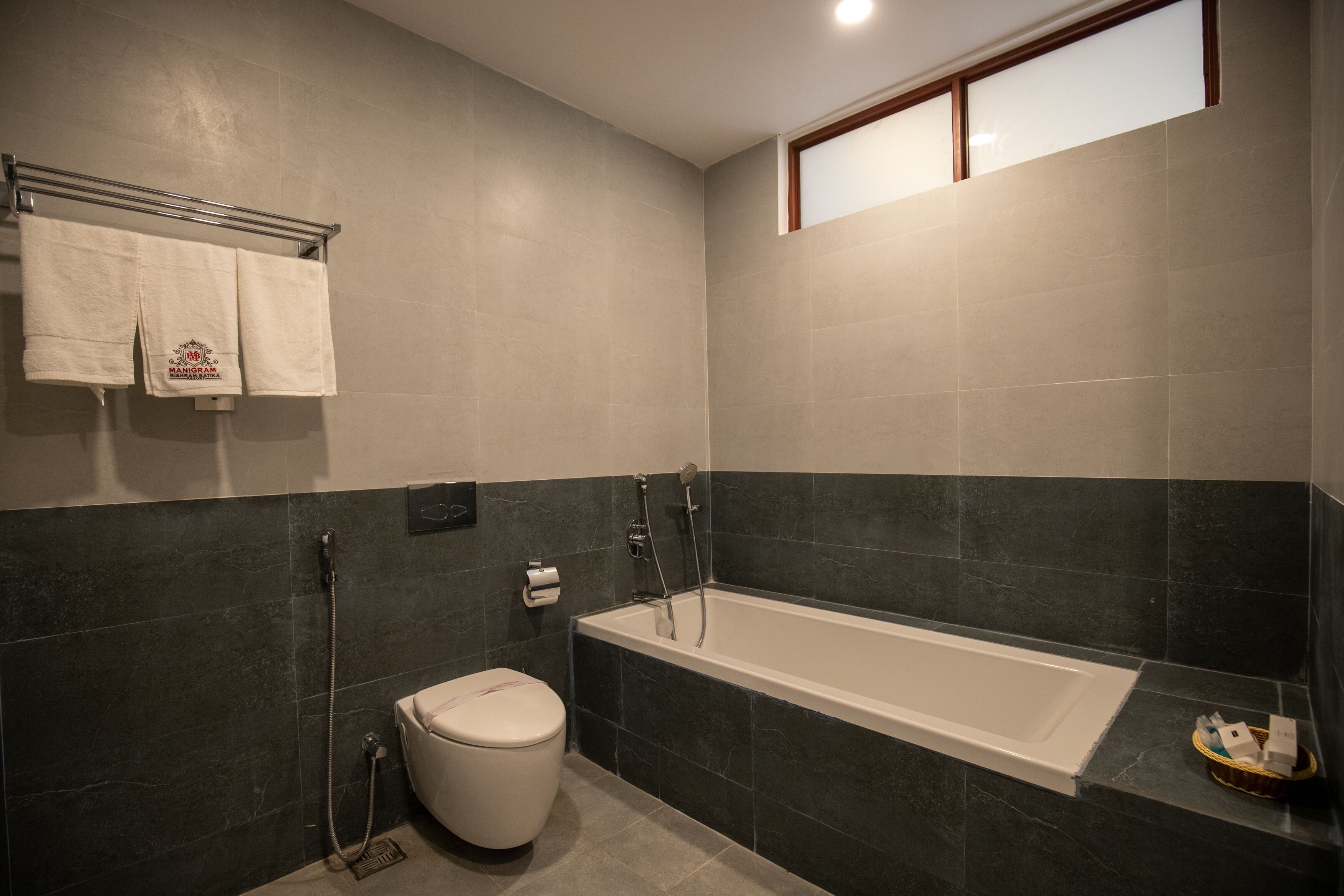 A modern bathroom with a bathtub, toilet, and towel rack.