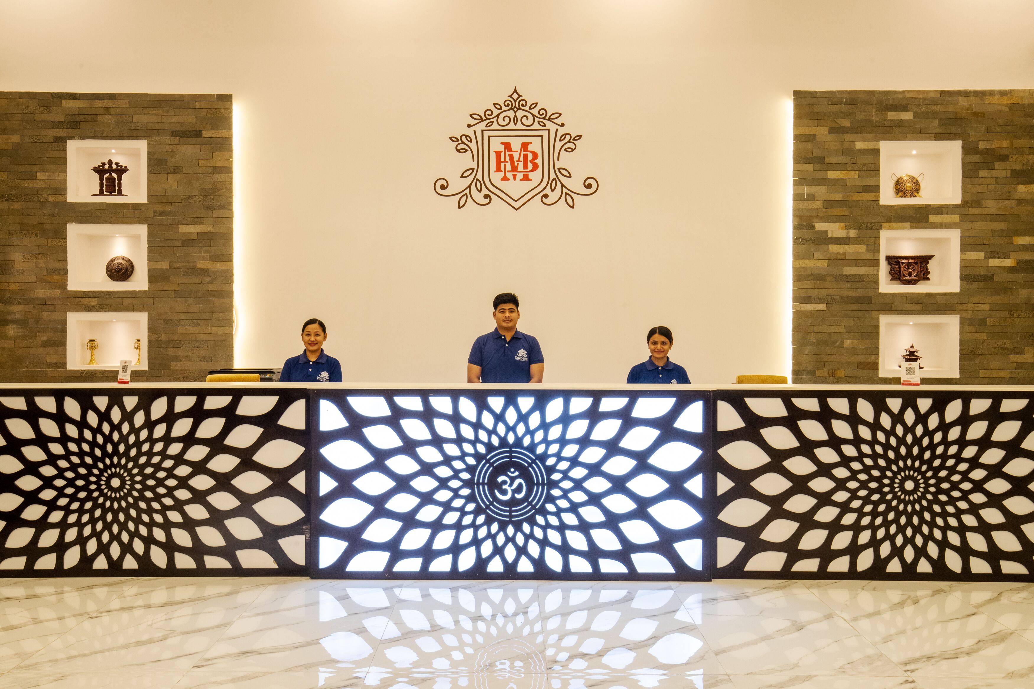 A reception desk with a geometric pattern, a logo above, and shelves with decorative items.