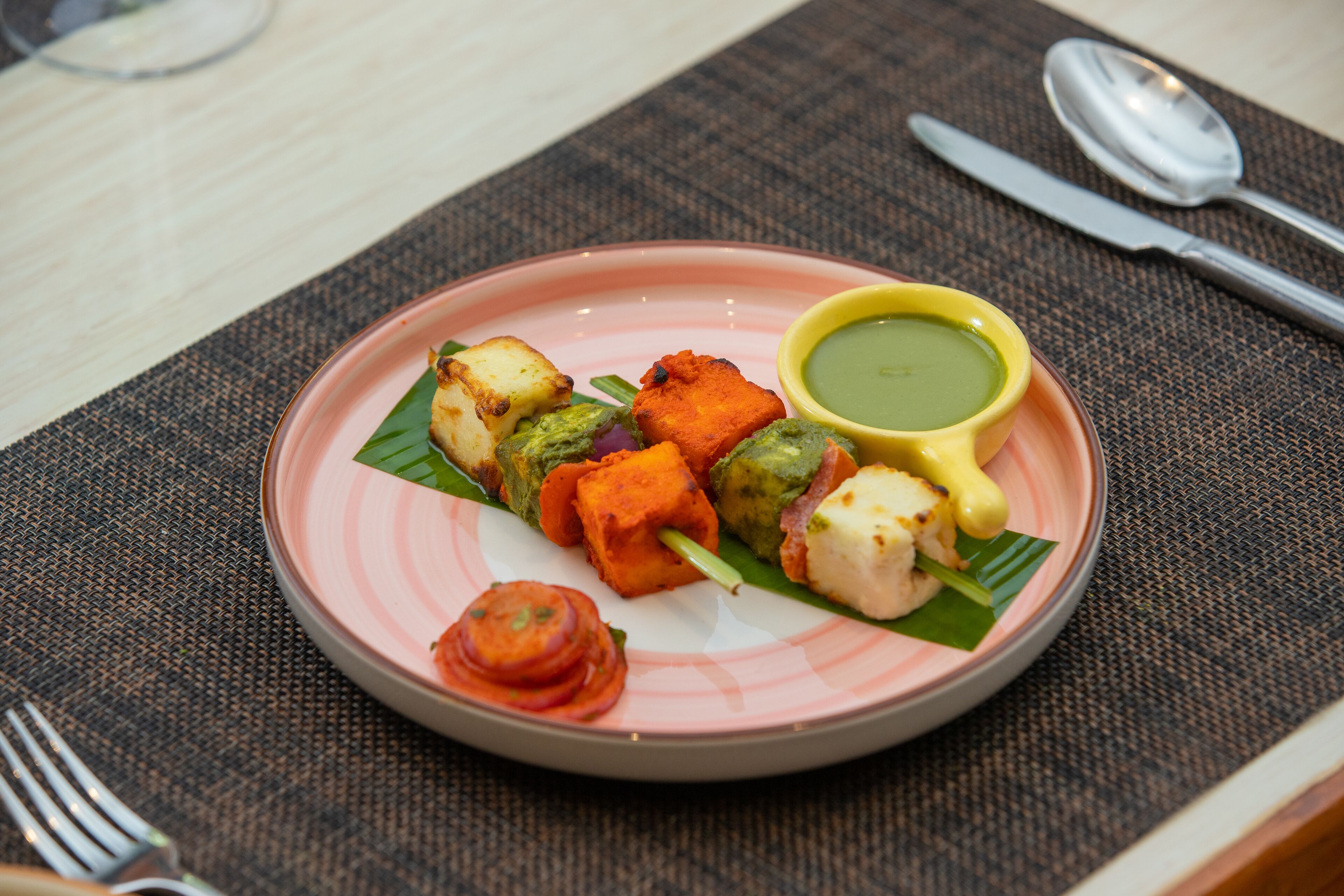 A plate of food with a variety of items including grilled vegetables and a green sauce.