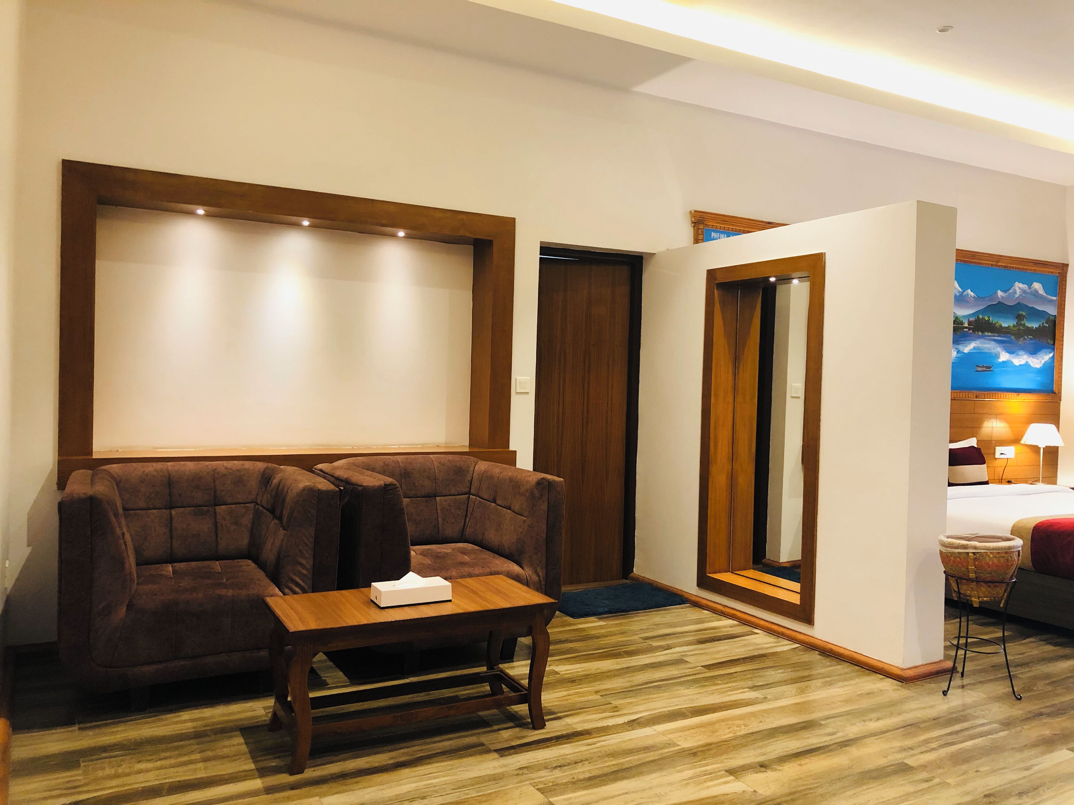 A hotel room with a wooden sofa, a small wooden table, and a bed with a nightstand.