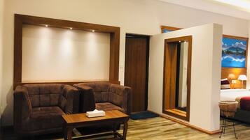 A hotel room with a wooden sofa, a small wooden table, and a bed with a nightstand.