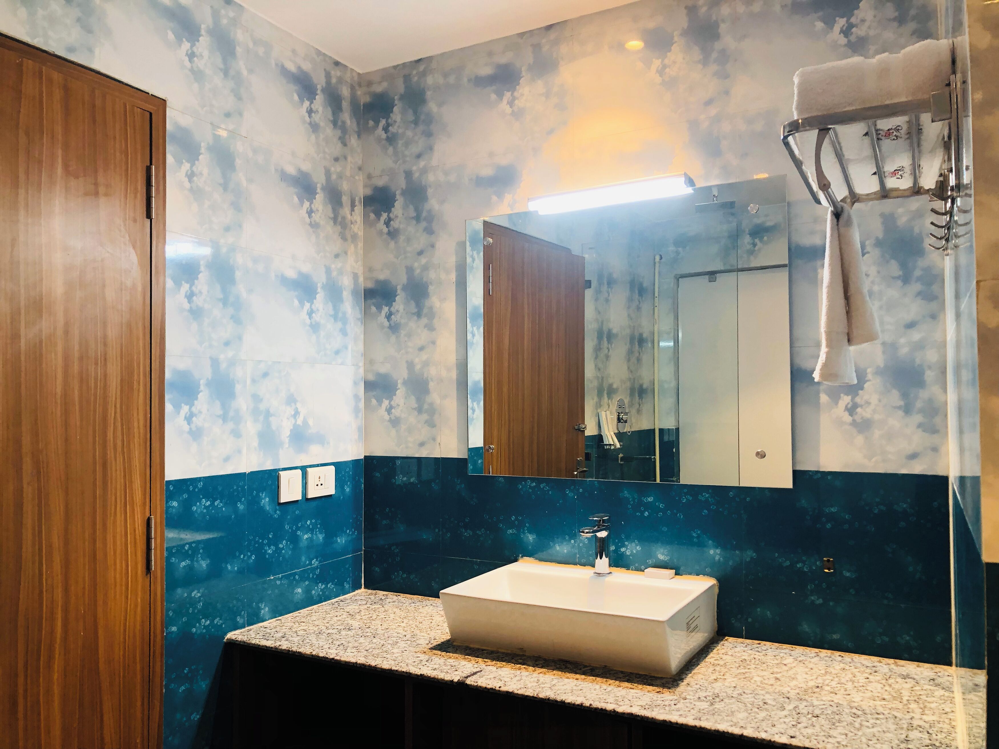Une salle de bain avec un mur en marbre, un lavabo et un miroir.