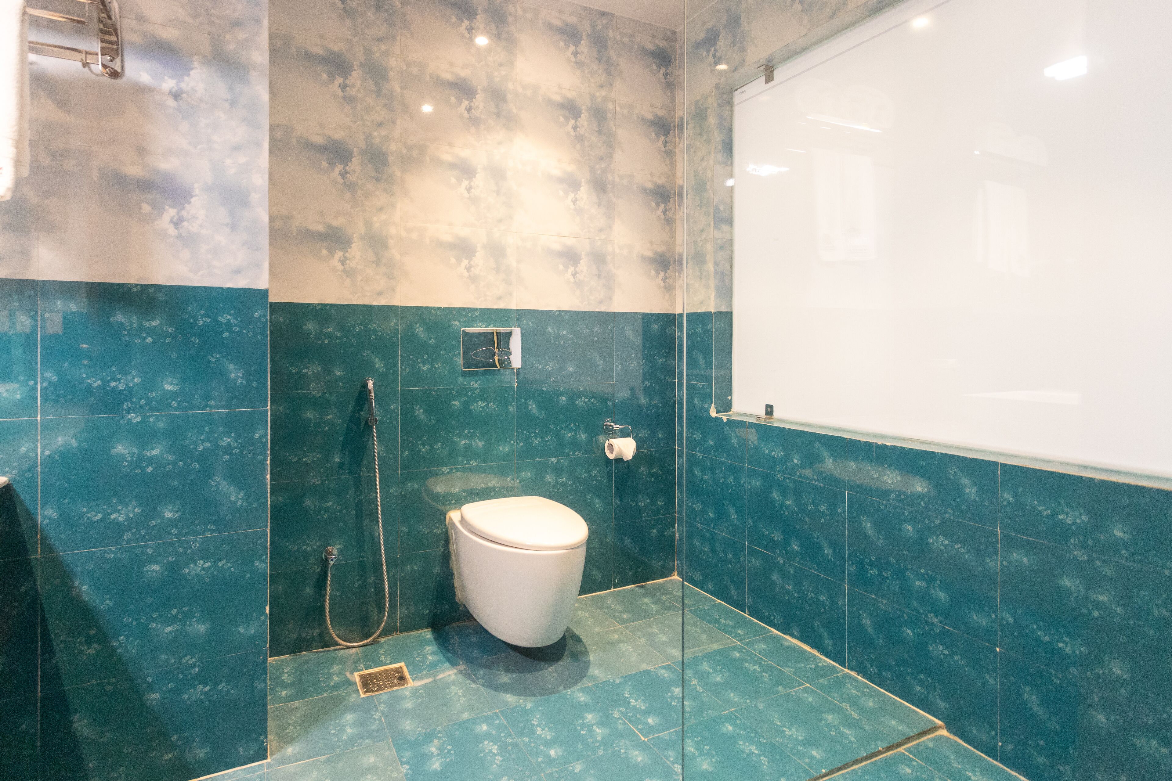Un baño con inodoro, ducha y perchero para toallas.