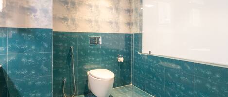 Un baño con inodoro, ducha y perchero para toallas.
