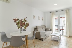 A modern living room with a dining table, gray chairs, a sofa, and a small white table.
