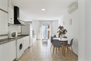 A compact kitchen with a washing machine, microwave, and a dining area with a table and chairs.