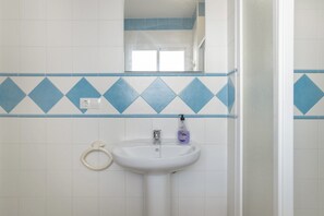 A bathroom with a white sink, a mirror, and a blue diamond-patterned tile border.
