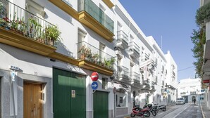 Vista de una calle con un edificio que tiene una puerta verde, un letrero azul indicativo y una motocicleta estacionada frente a él.
