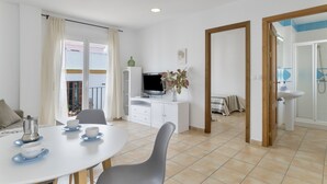 Habitación moderna y bien iluminada con comedor, televisión y baño con ducha.