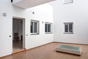 A white interior with three windows, a door, and a small pool area.