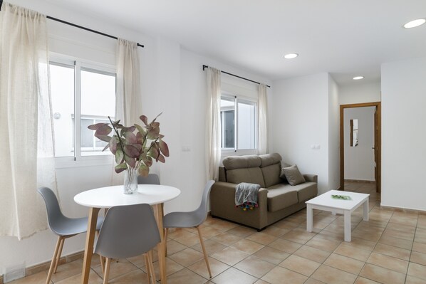 A modern living room with a dining table, grey chairs, a sofa, and a coffee table.