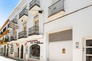 A white building with balconies, a storefront labeled 'muebles álba,' and a closed shutter on the right.