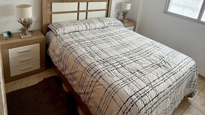 Een slaapkamer met een bed, nachtkastjes, een raam en wanddecoraties.