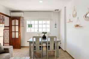 A dining area with a wooden table and chairs, a potted plant, and decorative wall hangings.