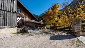 Une grange rustique, avec une allée de gravier menant à un mur de pierres.