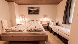 Une chambre avec un lit en bois, deux tables de chevet avec des lampes, une petite table de chevet, une fenêtre avec des rideaux et un tableau au mur.