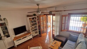 A living room with a sofa, TV, and shelves.