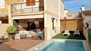 A two-story house with a swimming pool, outdoor furniture, and a balcony.