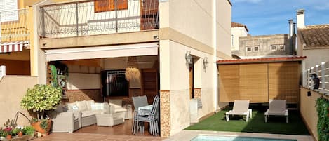 A two-story house with a swimming pool, outdoor furniture, and a balcony.