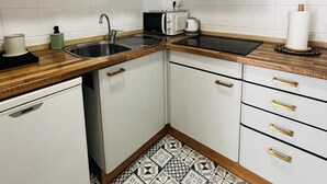 A compact kitchen with white cabinets, a stainless steel sink, a microwave, and a gas stove. - Charming apartment in Tossa de Mar (Tossa de Mar)