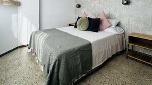 A bedroom with a bed, a nightstand, a wall-mounted light, and a decorative plant. - Charming apartment in Tossa de Mar (Tossa de Mar)
