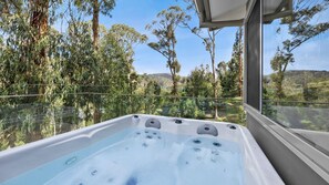 Ein Whirlpool mit Glasabdeckung, umgeben von üppiger Vegetation und freiem Blick auf die Landschaft.