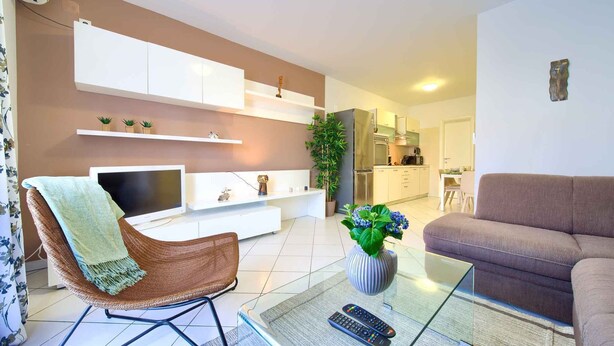 Ein modernes Wohnzimmer mit Fernseher, Sofa und einem Glastisch.