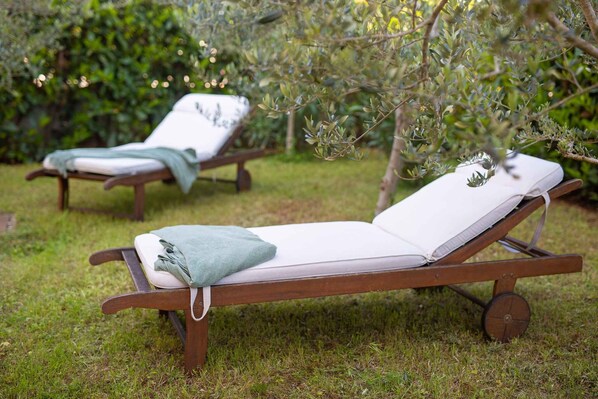 Two wooden lounge chairs with white cushions and a green towel, set on a grassy lawn with trees in the background. - Holiday apartment with terrace and air conditioning (Malinska)