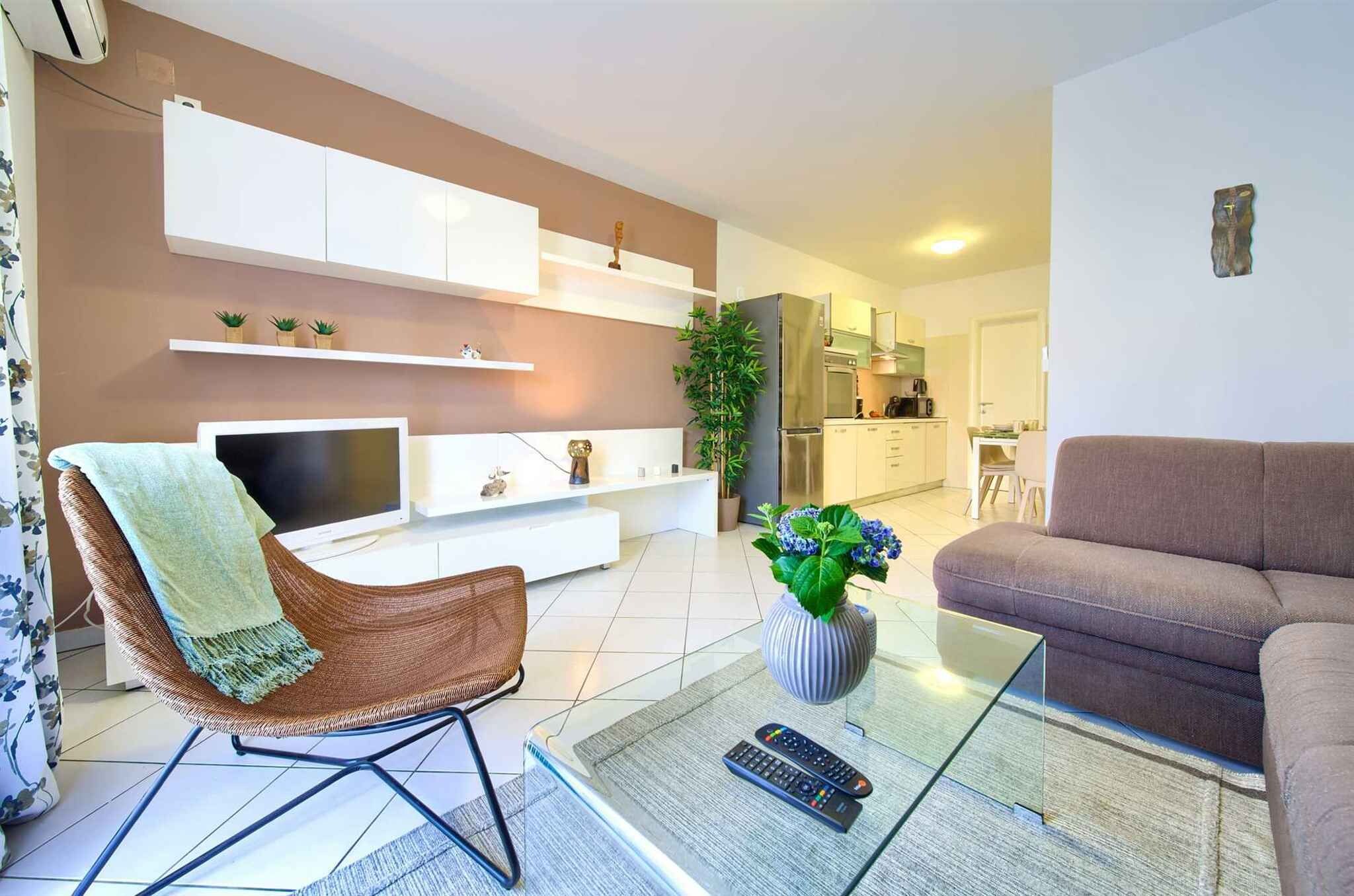 Een woonkamer met een televisie, bank, fauteuil en een glazen salontafel met afstandsbedieningen.