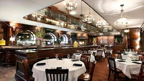 A restaurant with round tables, wooden chairs, and chandeliers. - New Lux Loft in Sundance Square Downtown FTW (Fort Worth)