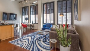 A modern living room with a sofa, a coffee table, and a large window. - New Lux Loft in Sundance Square Downtown FTW (Fort Worth)