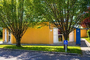 Un bâtiment portant un panneau indiquant qu’il est accessible aux personnes en fauteuil roulant, un panneau avec le numéro 19 et une porte portant l’inscription « 1 ».