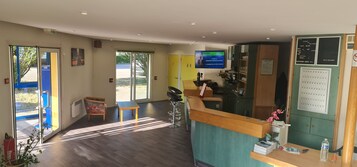Zona de recepción de un hotel con un mostrador de madera, una pantalla de televisión y un teléfono.