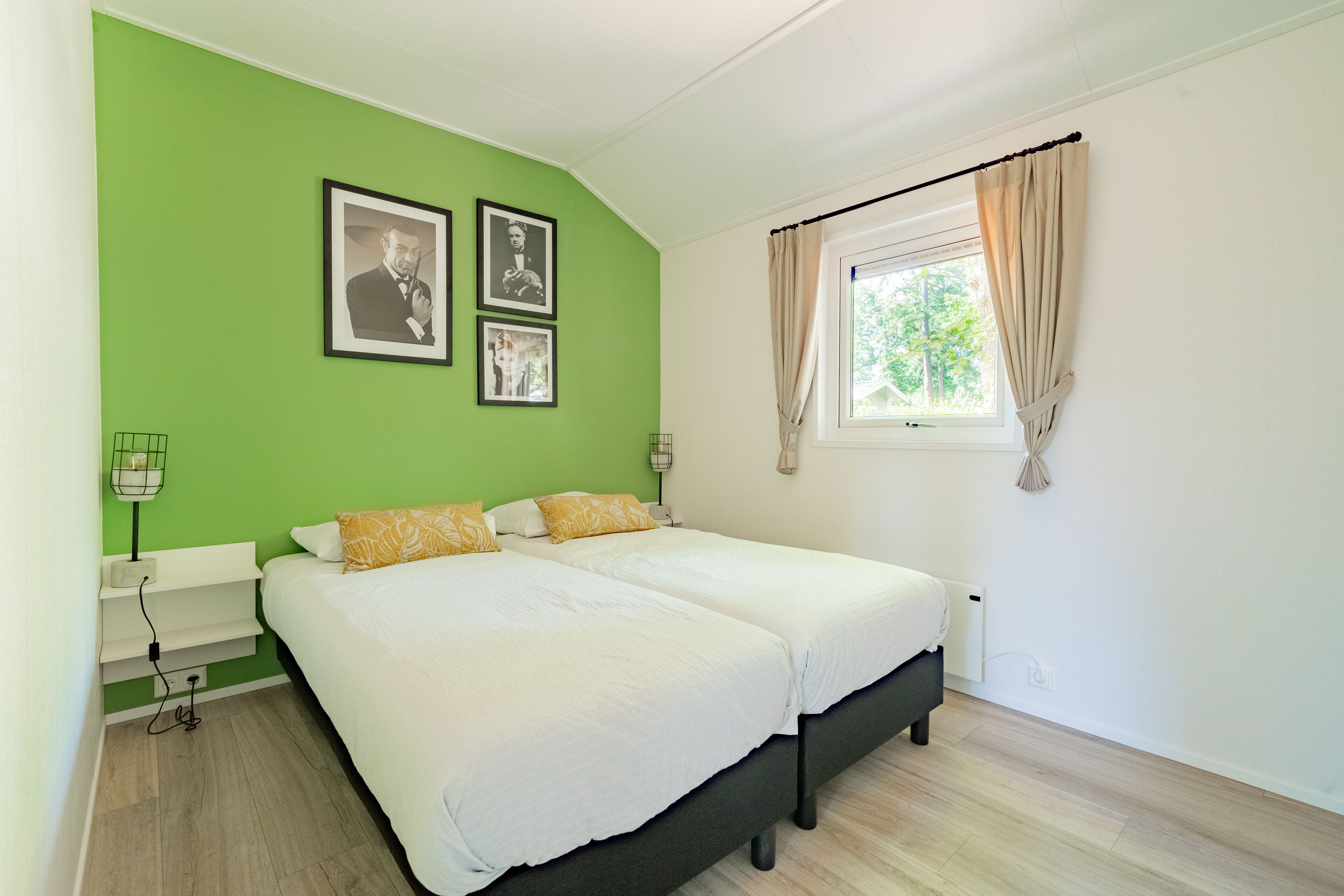 A bedroom with two beds, green walls, and a window with curtains.