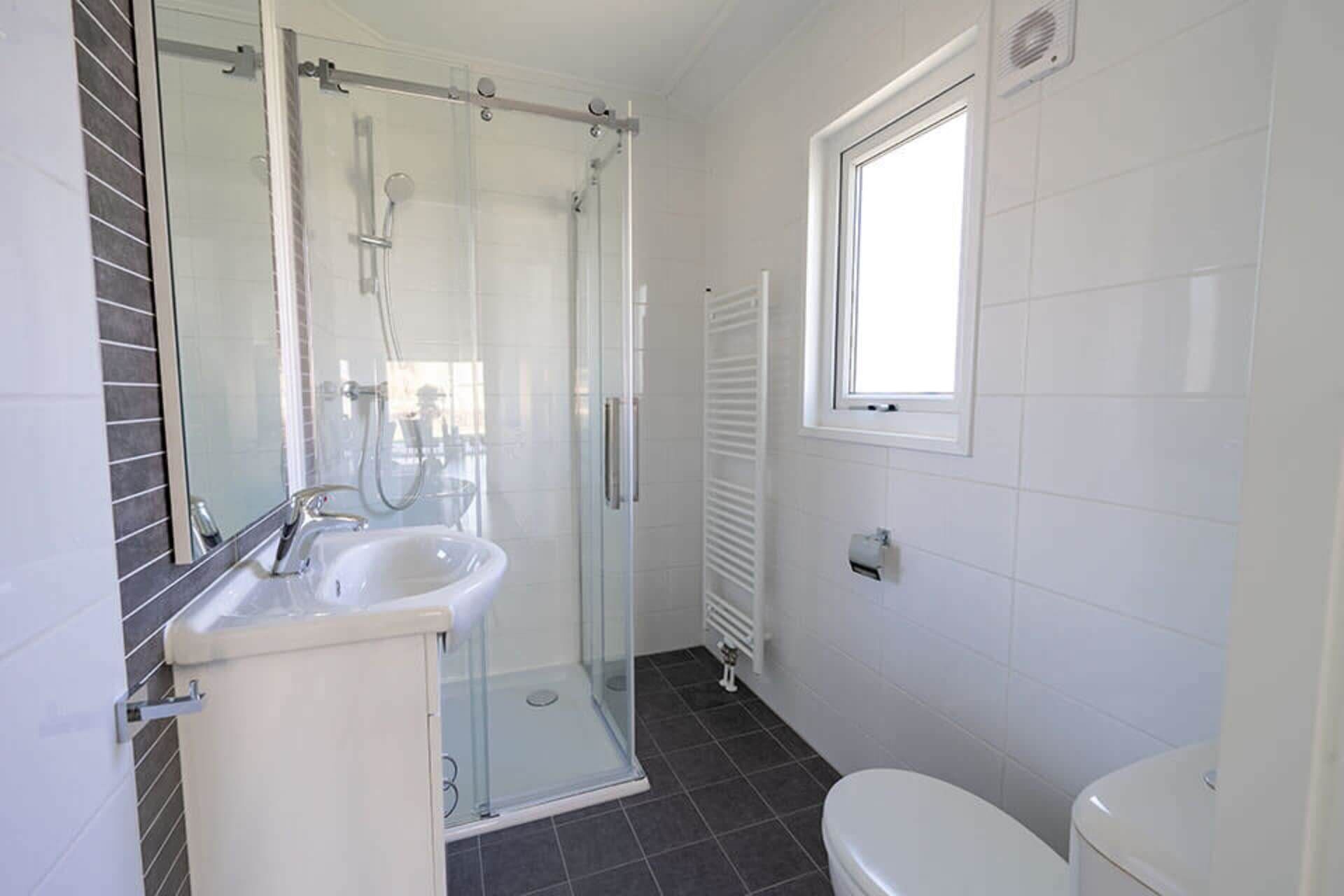 Un baño con ducha de vidrio, lavamanos e inodoro.