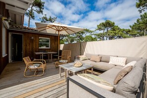 Une terrasse extérieure avec un canapé, des chaises, une table et un parasol.