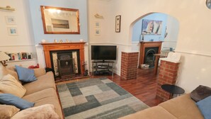 A living room with a fireplace, television, and a cozy seating area with a patterned rug.