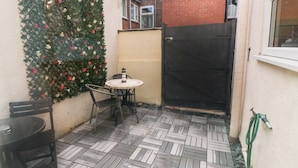 A small patio with a tiled floor, a round table, and chairs.