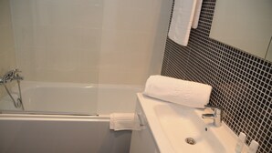 A bathroom with a bathtub, a sink, and a mirror.