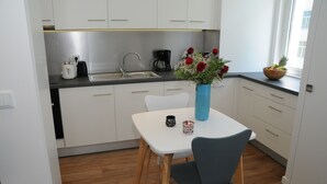 A small kitchenette with white cabinets, a sink, and a coffee maker. There is a table with a vase of flowers and a mug. - Charming Comfortable Apartment with Balcony 1 (Lisboa)