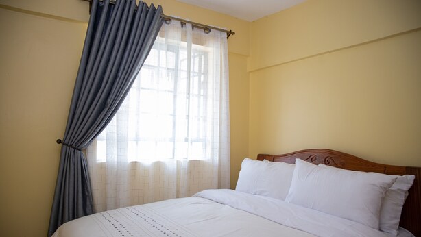 A bedroom with a bed, curtains, and a window. - Letai Homes Furnished Apartment (Nairobi)