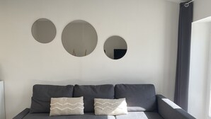 A modern living room with a grey sectional sofa, three wall-mounted mirrors, and a large window with curtains. - Apartment in the center of Castelnaudary (Castelnaudary)
