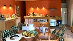 Een gezellige keuken met houten kastjes, een eettafel met stoelen en een koelkast.