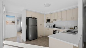 A modern kitchen with a stainless steel refrigerator, microwave, stove, and sink.