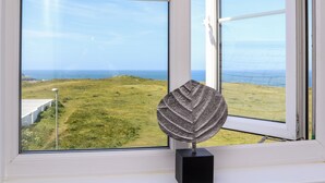 A window with a view of a grassy landscape and the ocean. - Penthouse 23 (Newquay)