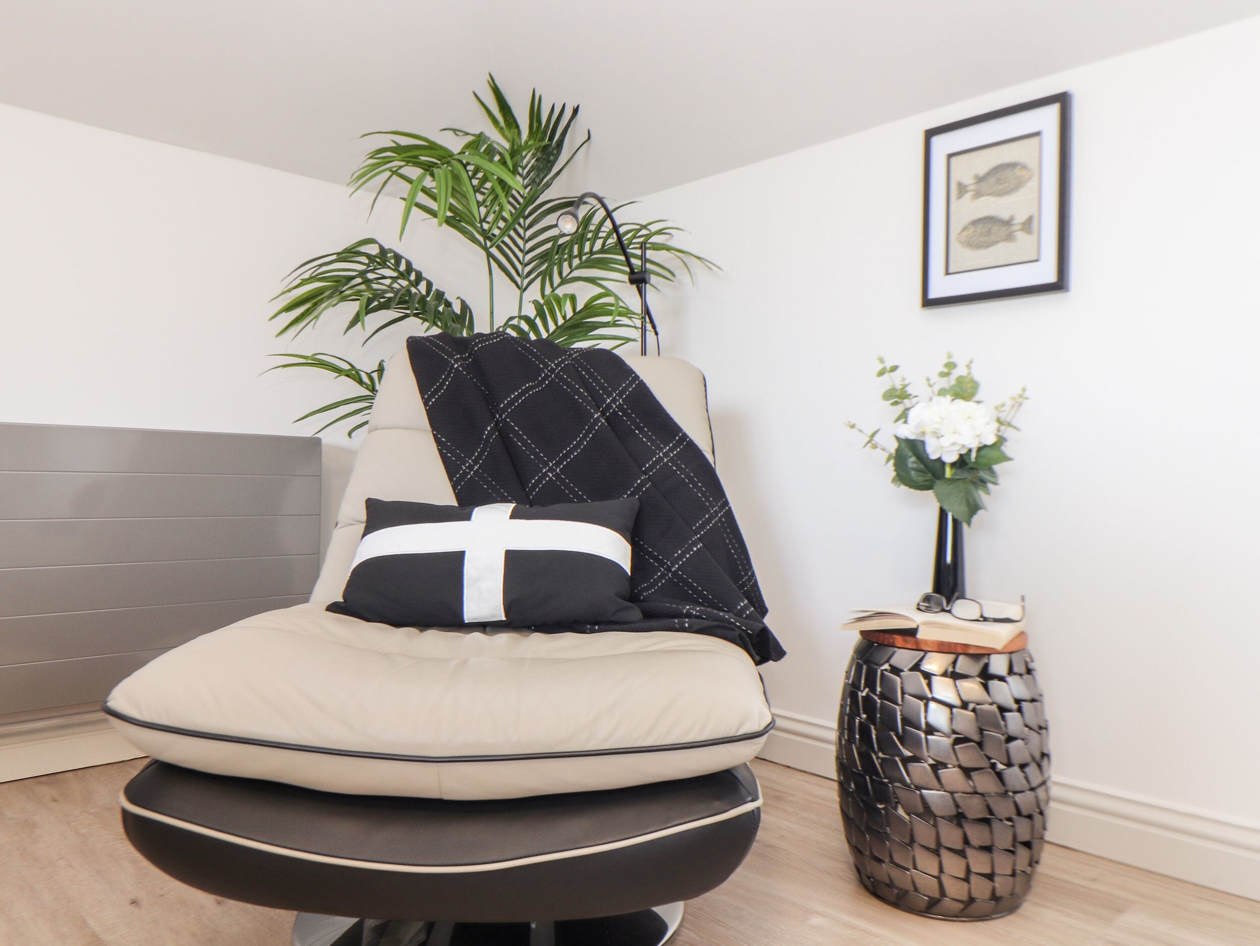 A modern bedroom with a bed, a potted plant, and a framed picture on the wall.