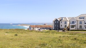 A coastal residential area with a large building featuring multiple balconies and a view of the sea. - Penthouse 23 (Newquay)