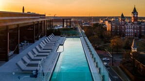 A rooftop pool with lounge chairs and a view of a historic building with a clock tower. - Laurel Hotel and Spa (Auburn)