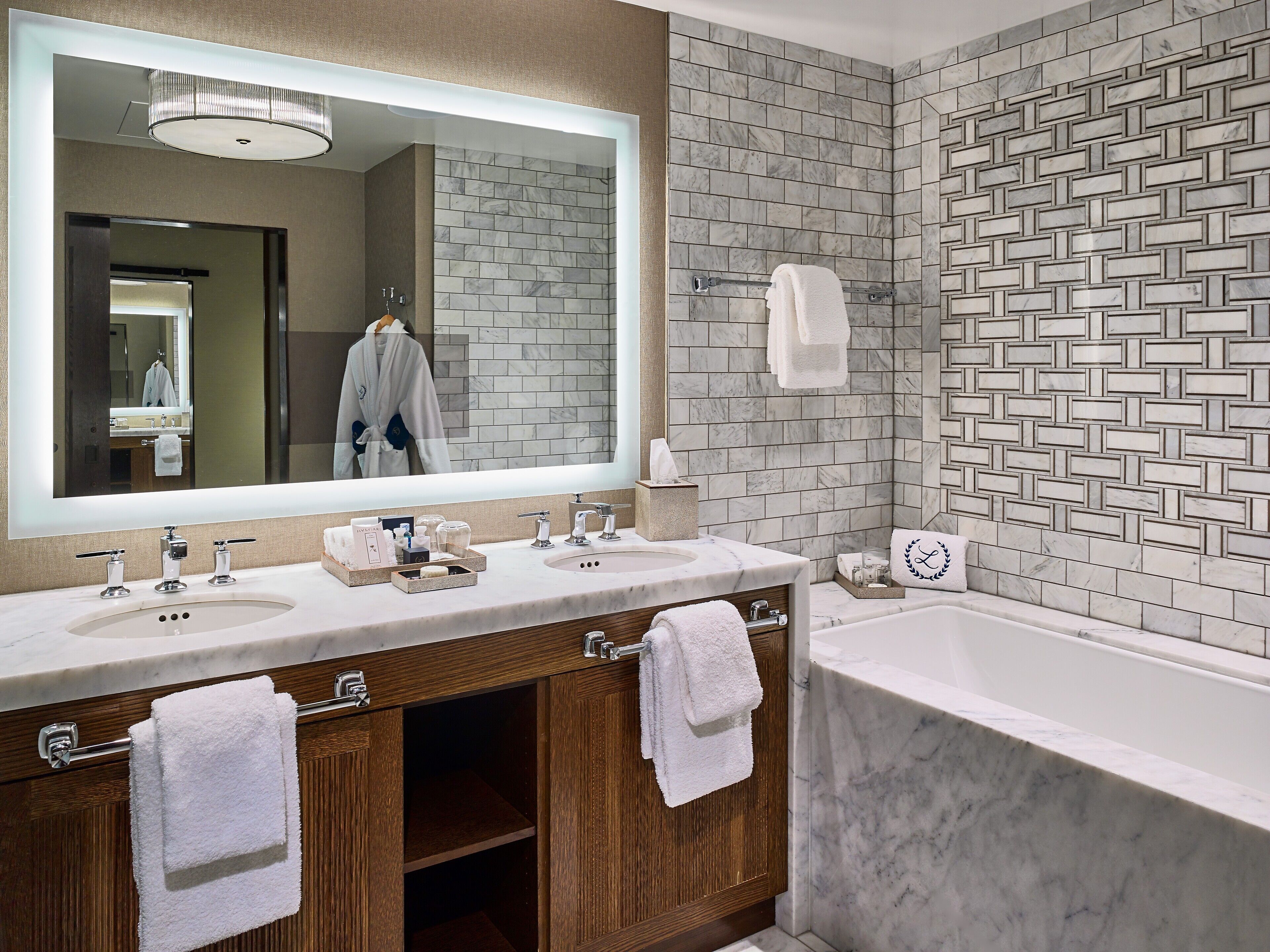Un baño moderno con dos lavamanos, un espejo grande y una bañera.