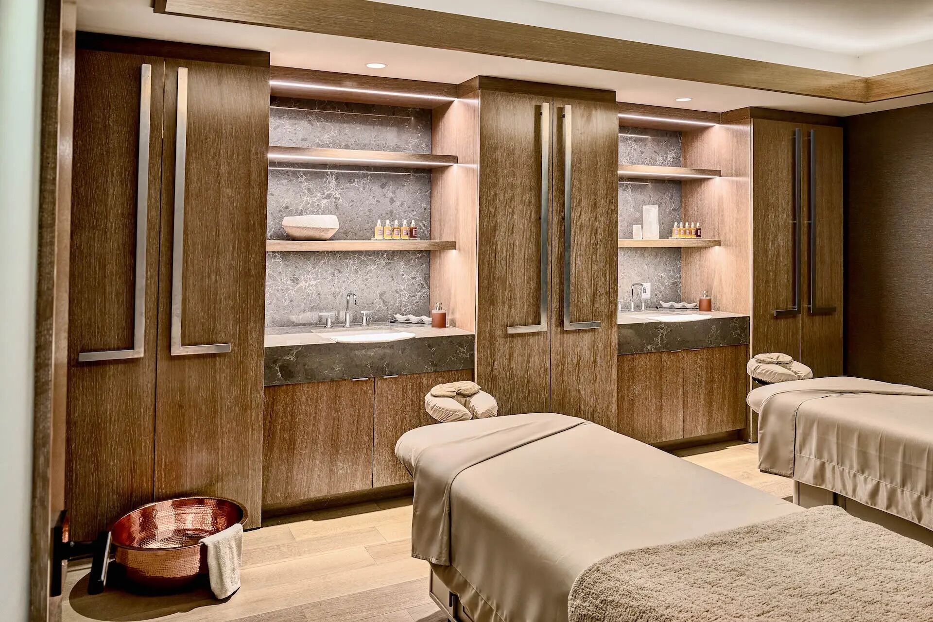 A modern bathroom with wooden cabinets, marble countertops, and a massage table.